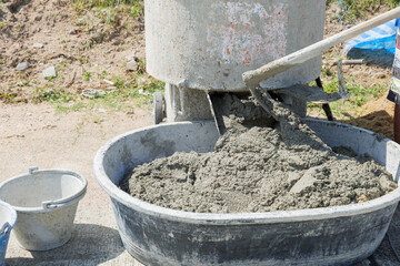 Concrete preparation in progress: cement mixer combines gray mortar and sand into a smooth mix.