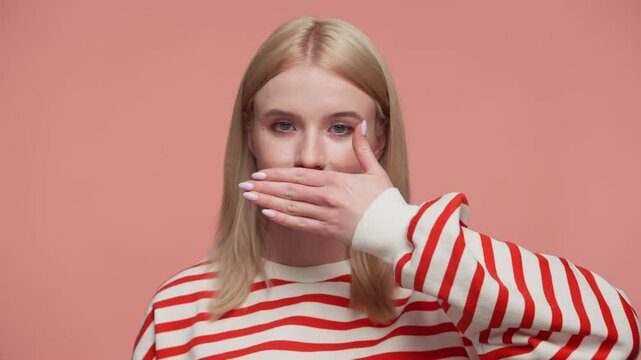 Woman covering mouth with hand in silence on pink