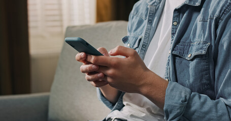 A young man uses his phone to text and explore websites, focused on digital interaction.
