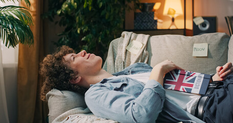 A focused student studies for a language test by reading vocabulary from a dictionary and reviewing...