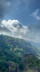 Majestic Mountain Landscape Under a Cloudy Sky: A Breathtaking View of Lush Green Hills and Dramatic Cliffs