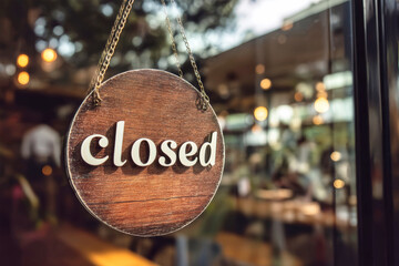 Closed sign hanging on glass door of cafe indicating operational hours for customers and staff
