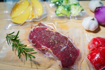 Sealer for vacuum packing with plastic bag of raw meat on wooden table, to preserve meat, flat lay, top view.