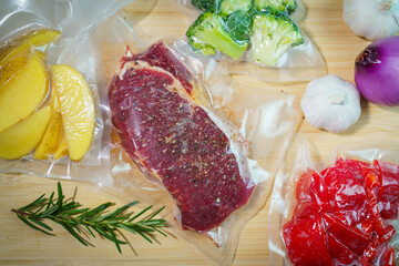 Sealer for vacuum packing with plastic bag of raw meat on wooden table, to preserve meat, flat lay, top view.