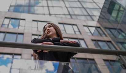 Portrait of a beautiful woman against the background of a modern high-rise building. © OLGA RA