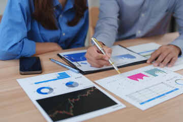 Business colleagues analyzing financial charts and graphs at office desk