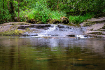 A wonderfully serene stream features a gentle waterfall gracefully surrounded by vibrant greenery, creating an idyllic and peaceful natural escape for all visitors, Slieve Bloom Mountains Ireland