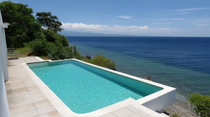 Fototapeta premium Hotel infinity pool overlooking ocean, turquoise water, clear sky, luxurious vibe.