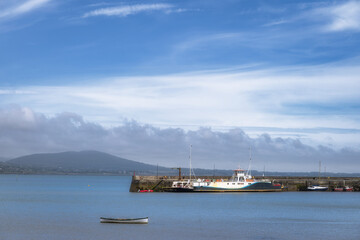 A picturesque harbor scene brings to life beautiful boats docked peacefully against a stunning backdrop of serene waters and softly cloudy skies that inspire tranquility, Carlingford, Ireland