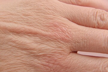 Fototapeta premium This Macro View Presents a Detailed Close-Up of a Wrinkled Hand, Highlighting Its Unique Skin Texture, Characterized by Fine Lines and Creases. The Image Emphasizes the Intricate Natural Patterns