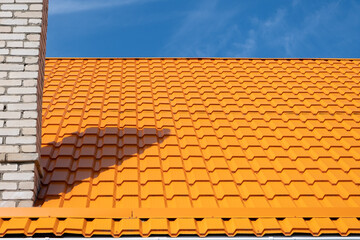 Bright orange roof of metal roofing against blue sky