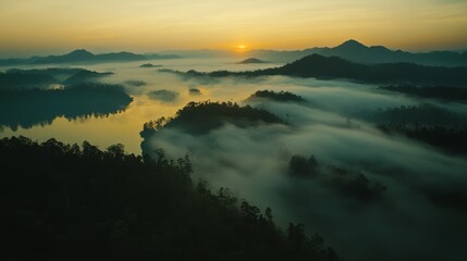 Fototapeta premium From above, we see fog covering mountains as the sun rises in Phang Nga, Thailand. It's a wide view of nature in Southeast Asia. 