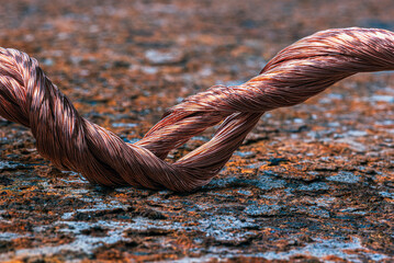 Tangled bundle of copper wire lies on a rust-covered industrial steel surface