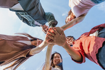 Multiethnic group of young friends stacking hands outdoors - Happy group of diverse young friends...