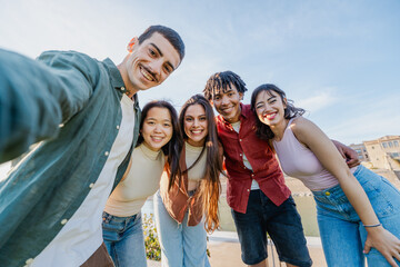 Happy multicultural friends posing for selfie - Smiling group of diverse young people taking selfie outdoors. Concept of friendship, youth and summer travel.