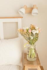 Bouquet of tulips and mimosa flowers in a vase on a bedside table. Interior decoration with fresh flowers in a home setting.