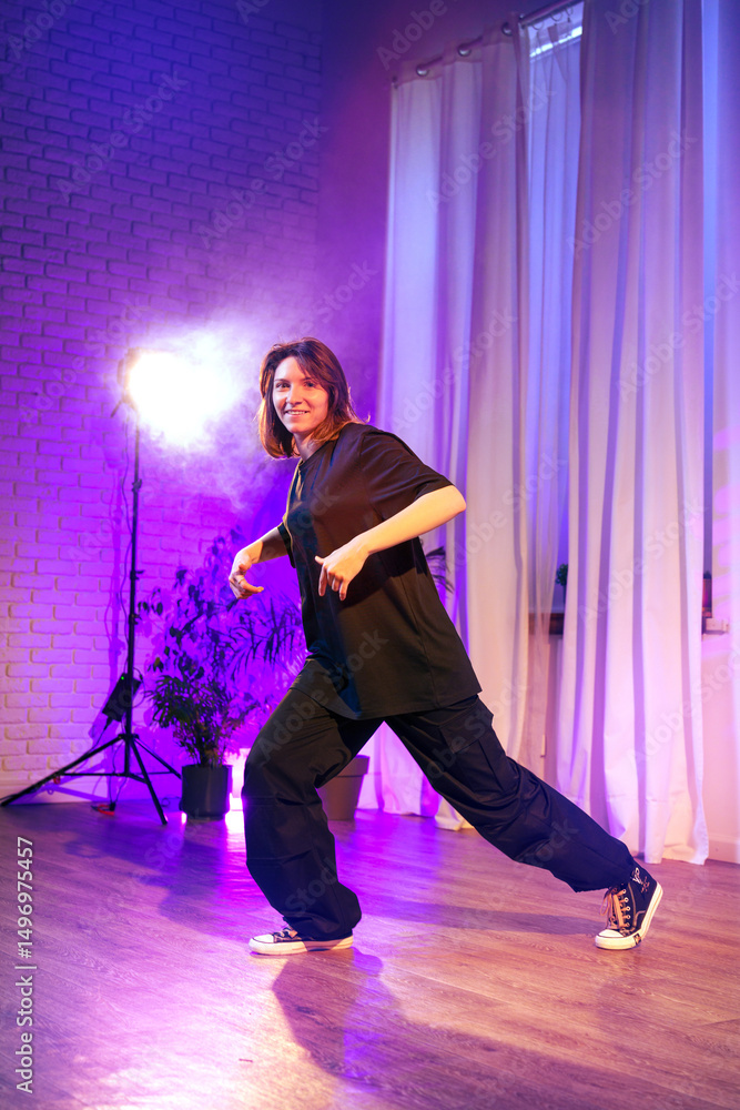 Poster dancer performs dynamic routine in studio with colorful lighting and soft curtains during evening se