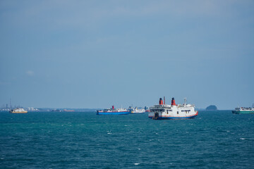 Fototapeta premium Numerous Boats and Ships Sailing on Calm Blue Waters Under a Clear Sky in Coastal Environment