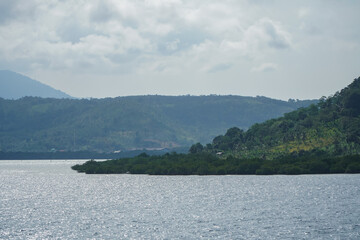 Serene Landscape View of Calm Water and Lush Green Hills Under a Cloudy Sky