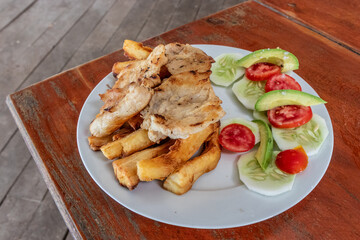 Dish in peruvian amazon - caiman fillet with fried cassava and salad