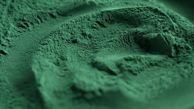 Heap of green spirulina algae powder spins, close up. Green powder super food, macro, rotation. Dietary supplement to improve health. Seaweed superfood concept. Healthy food background