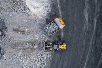 Industrial excavator loader of gold ore to truck, mining industry, Aerial top view
