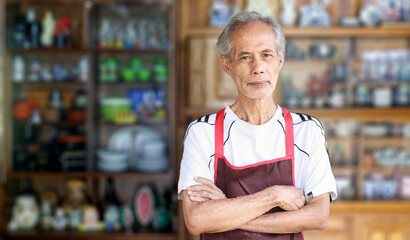 An elderly Asian man sells merchandise as a hobby.