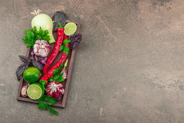 Cooking background in warm brown tones. Set of fresh vegetables and herbs, preparation spices