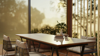 A coffee cup and books on wooden table with steel armchairs in dining hall of a restaurant or cafe.