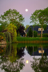 Quiet view of the reflection of the moon in a pond in a Dutch suburb
