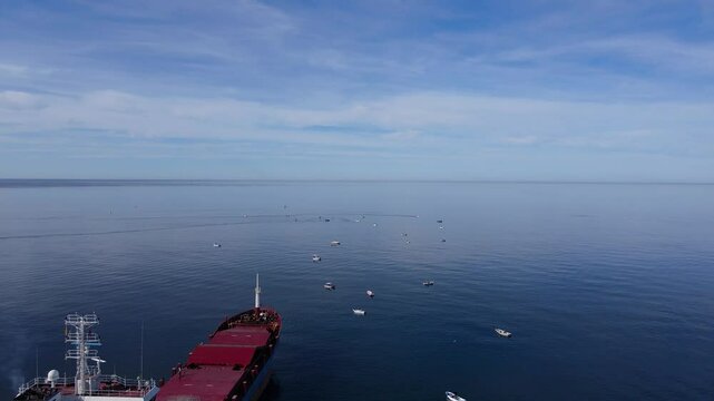 Footage of amateur fishermen fishing with their boats and a cargo ship.