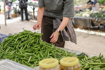 Young woman choosing fresh organic vegetables at a local market. Concept of eco lifestyle,...
