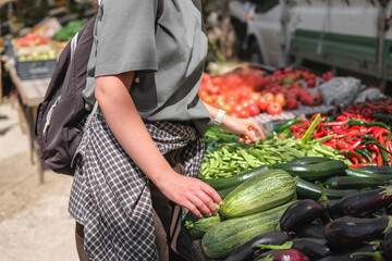 Young woman choosing fresh organic vegetables at a local market. Concept of eco lifestyle,...