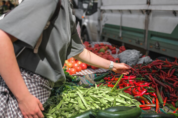 Young woman choosing fresh organic vegetables at a local market. Concept of eco lifestyle,...