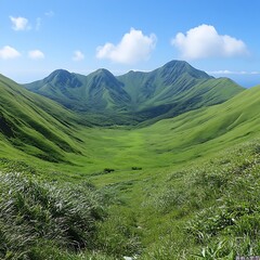 Obraz premium Lush green valley nestled between mountains under a vibrant blue sky.
