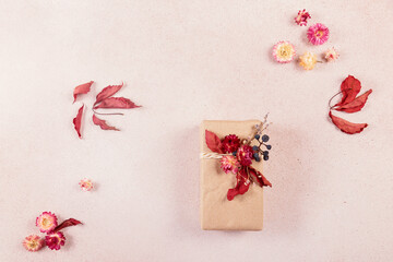 Autumn creative holiday present. Handmade paper gift box with foliage dried leaves on light table. Gift Wrapping. Thanksgiving day, autumn holidays, fall background