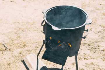 Steel kazan, a large cast iron cauldron, on a fire pit for cooking outdoors. Outdoor cooking...