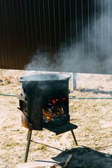 Steel kazan, a large cast iron cauldron, on a fire pit for cooking outdoors. Outdoor cooking...