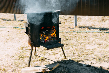 Steel kazan, a large cast iron cauldron, on a fire pit for cooking outdoors. Outdoor cooking...