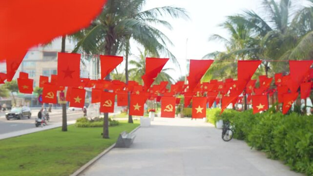 Vietnamese street lined with red flags bearing yellow stars and sickle, displaying national pride during independence day commemorative event with symbolic patriotic imagery