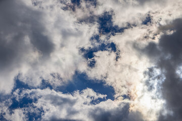 The sky is filled with clouds of varying shades, with sunlight filtering through gaps, forming a dynamic interplay of light and shadow, suitable for design and editing needs