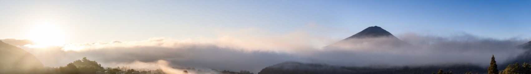 Early morning mist drapes over the foothills of Mount Fuji while the first sunlight gently...