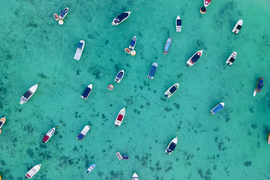 Aerial top view of Sailing and fish boats on turquoise clear tropical water of "trou aux biches" beach, Mauritus island, indian Ocean
