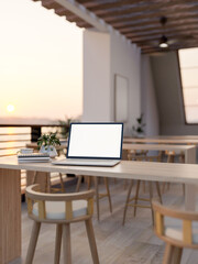 White screen laptop with books and coffee cup on wooden counter table long table on the terrace.