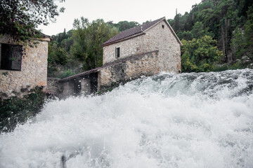White water cascading over the rocks under old stone watermills in the lush Krka national park,...
