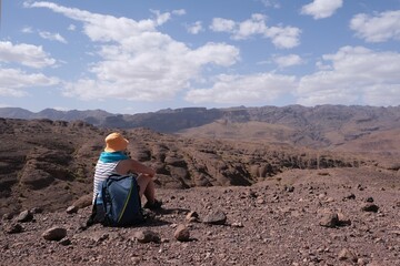 Amazing mountain landscapes of Jebel Saghro with volcanic rocks eroded by wind and time and sitting woman. Atlas, Anti Atlas, Morocco © Iwona