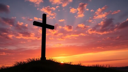Silhouette of a cross on a hill at sunset with orange and pink clouds in the background sky landscape