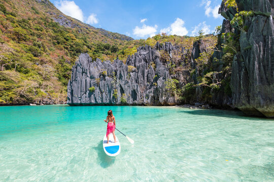 Young asian woman on paddleboard in a lagoon, El Nido, Philippines