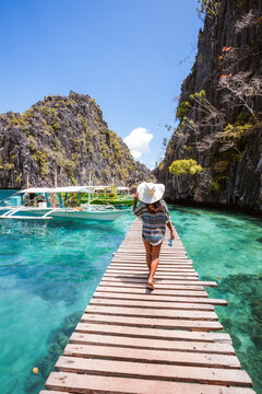 Young woman walking on a jetty near the turquoise sea, Coron island Palawan, Philippines