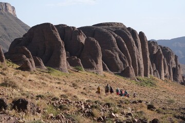 Amazing mountain landscapes of Jebel Saghro with volcanic rocks eroded by wind and time and group of trekking tourists. Atlas, Anti Atlas, Morocco
